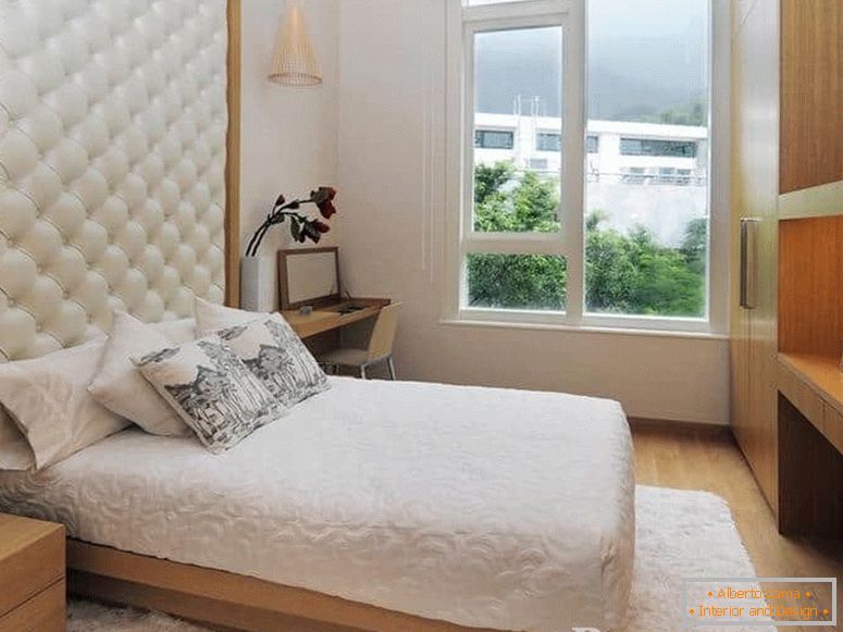 Ein kleines Bett mit einem Lederkopfteil und im Schlafzimmer mit einem großen Fenster