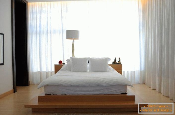 Das Bett gleicht einem großen weichen Federbett, das sich auf einem hohen Laufsteg aus Holz befindet. Vorhänge aus weichem, durchscheinendem, fliegendem Stoff machen die Atmosphäre im Raum romantisch und entspannend. 