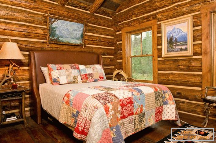 Ein Schlafzimmer im rustikalen Stil in einem Jagdhaus. Bemerkenswerte Dekoration der Wände mit Hilfe eines Blockhauses. 