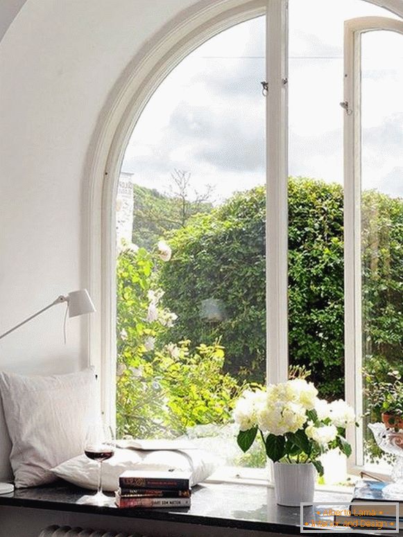 Fensterdekoration mit Kissen, Büchern, Blumen