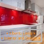 Weiße Möbel und eine rote Schürze im Inneren der Küche