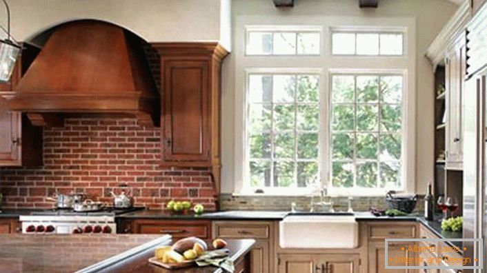 Richtig eingerichtete Küche im rustikalen Stil. Die Haube und die dunklen Holzschränke sind mit einer Mauer aus Ziegelsteinen kombiniert.