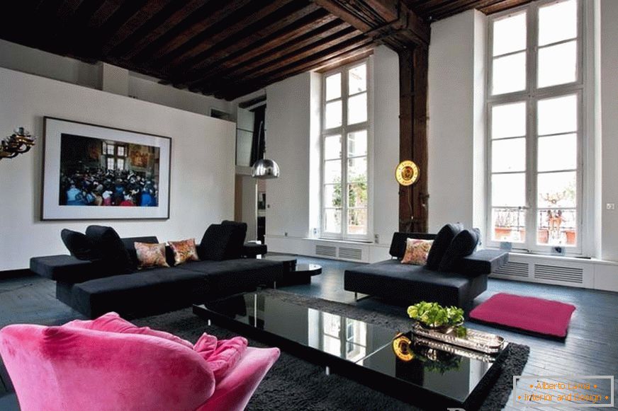 Schwarze Sofas und ein rosa Sessel im Zimmer