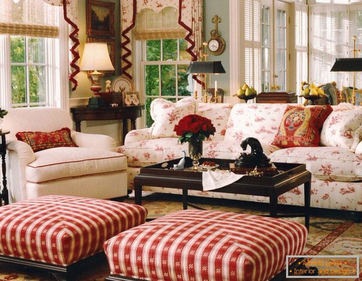 Ein einfaches, bescheidenes und gemütliches Wohnzimmer im englischen Stil in einem kleinen Landhaus. Akzente aus Rot machen die Atmosphäre im Raum entspannt und fröhlich.