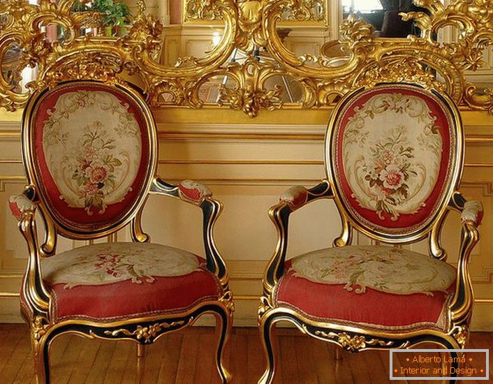 Durchbrochener goldfarbener Stuck auf dem Spiegel und Stühle mit roter, weicher Polsterung - helle Vertreter des Barockstils.