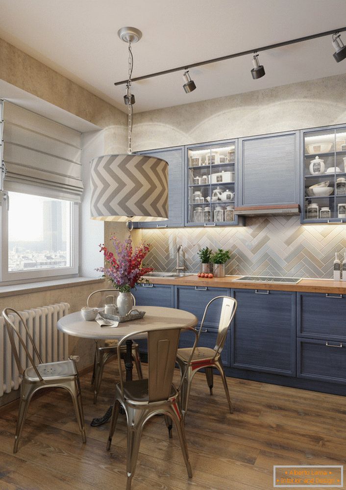 Die blassblaue Farbe des Küchensets ist eine ausgezeichnete Lösung für die vielseitige Küche. Ein Beispiel für perfekt ausgewählte Beleuchtung, die den Arbeitsbereich und den Esstisch separat beleuchtet.