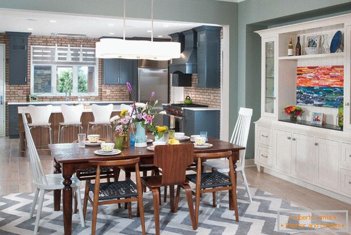 Eine große eklektische Küche ist in einen Arbeits- und Essbereich unterteilt. Die Möbel der weißen Farbe sind mit den Elementen der Innenausstattung der dunkelbraunen Farbe kombiniert.