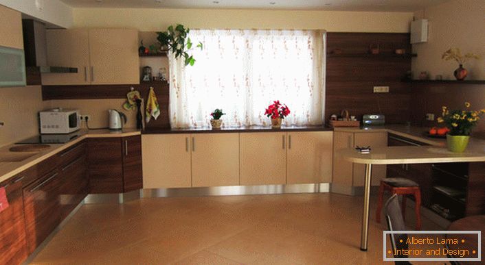 Eine angenehme große Küche in hellen Beigetönen mit Mahagoni Akzenten von komfortablen Möbeln.