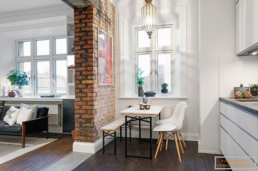 Ein Bogen aus unverputztem Mauerwerk teilt den Raum in ein Wohnzimmer und eine Küche
