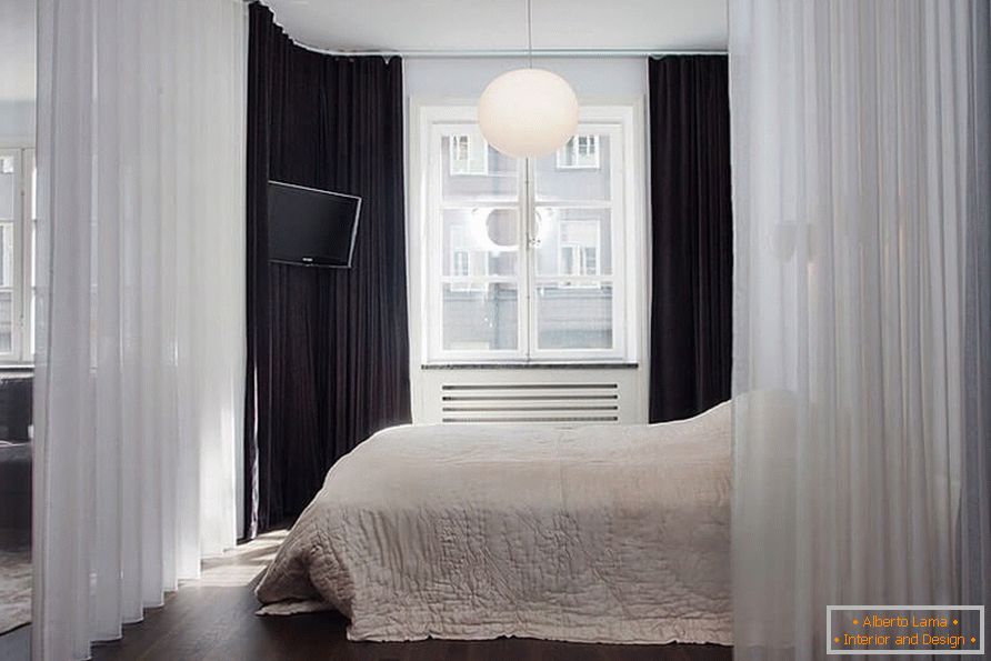 Ein Bett mit einem Vorhang in einer Einzimmerwohnung von 36 qm
