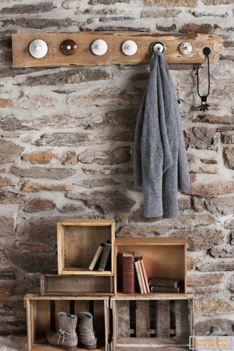Rustikale DIY Garderobe im Zimmer mit Steinmauer; Garderobenhaken aus alten Porzellandeckeln und alte Holzkisten auf dem Boden als Ablage