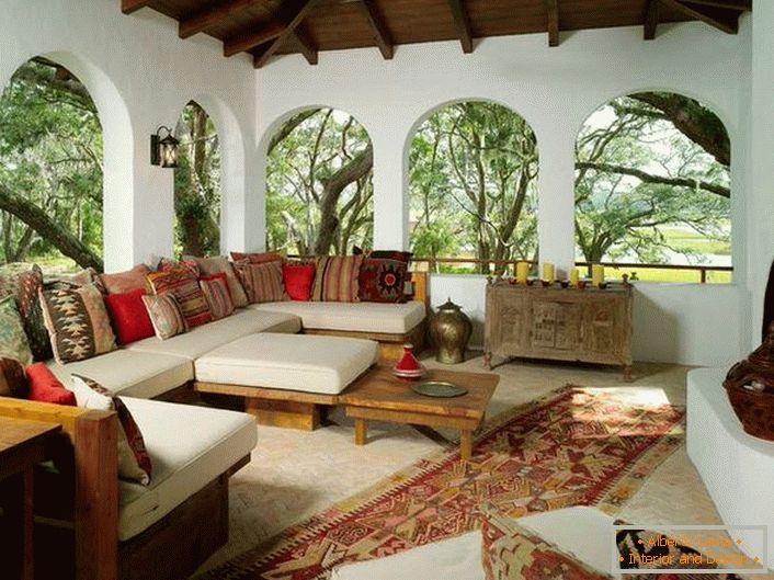 Die Veranda des Landhauses ist im mediterranen Stil eingerichtet. Ein interessantes Merkmal ist die Einrichtung mit vielen bunten Kissen.