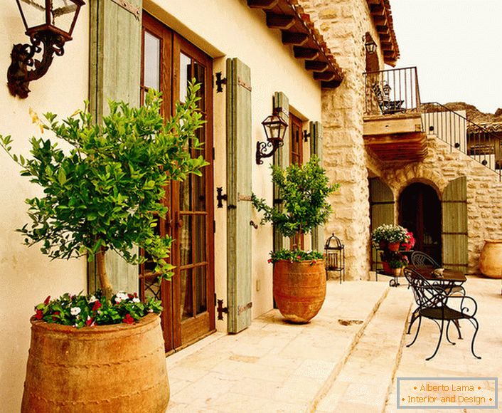 Die Terrasse в средиземноморском стиле украшают горшки с живыми растениями. Привлекательный дизайн, мебель с витиеватыми спинками, керамические горшки создают уютную, расслабляющую атмосферу. 