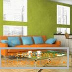 Orange Sofa mit blauen Kissen gegen den Pistazienwandhintergrund