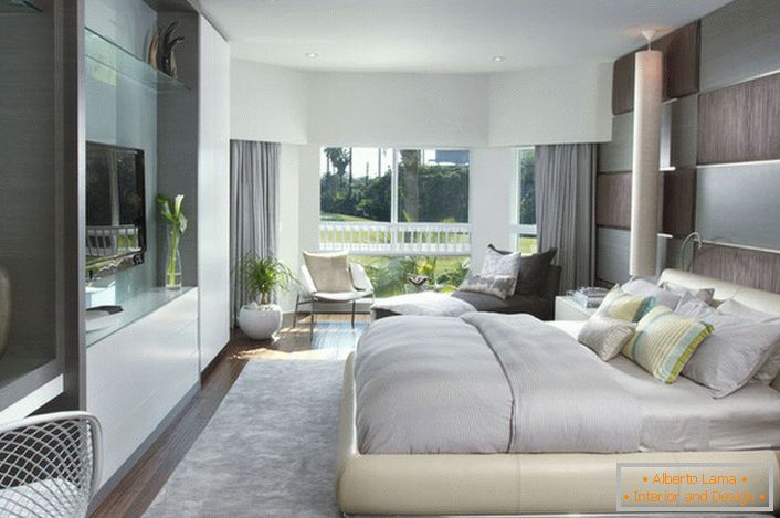 Weiches, großes Bett im Schlafzimmer in einem modernen Stil. Möbel mit einer glänzenden Oberfläche passen gut zur Gesamtzusammensetzung des Interieurs.