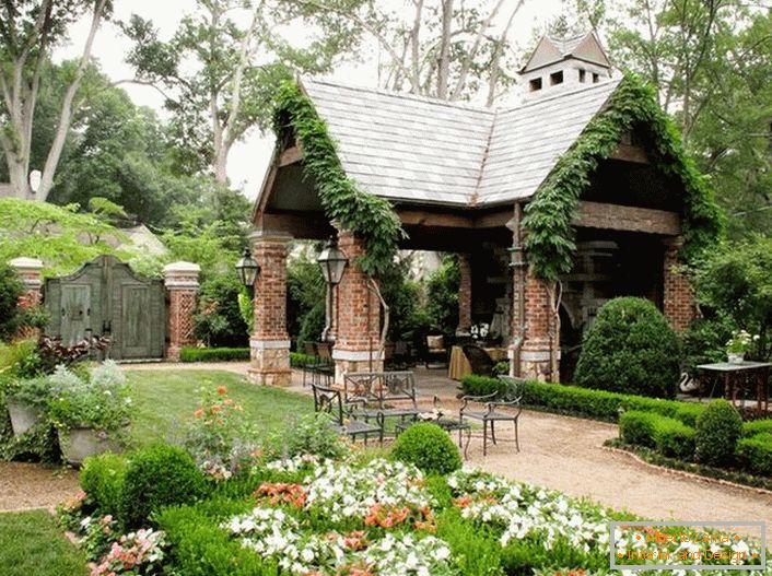Die elegante Einfachheit eines offenen Pavillon im Stil eines Chalets sieht organisch in einem luxuriösen, gemütlichen Garten aus. 