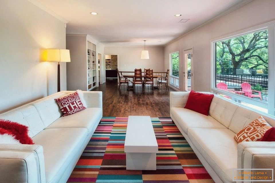 Wohnzimmer mit weißen Sofas und farbigem Teppich