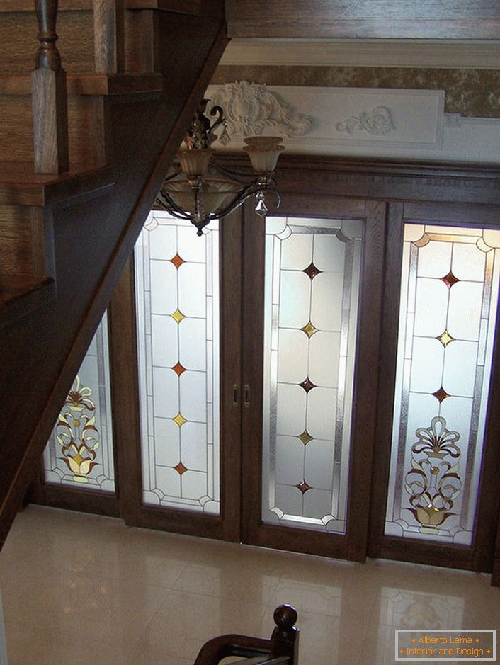 Türen mit Glaseinsätzen sind mit einer matten Buntglasfolie mit einem unkomplizierten Muster verziert. Nicht protzig, zurückhaltend gestaltet sich das Design der Türen organisch in das klassische Interieur der Halle. 