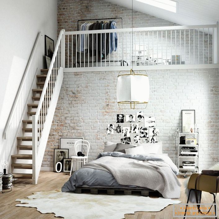 Das Schlafzimmer im skandinavischen Stil ist funktional in zwei Zonen unterteilt. Eine Holztreppe führt in den zweiten Stock, wo sich ein kleines Ankleidezimmer auf dem Bett befindet.