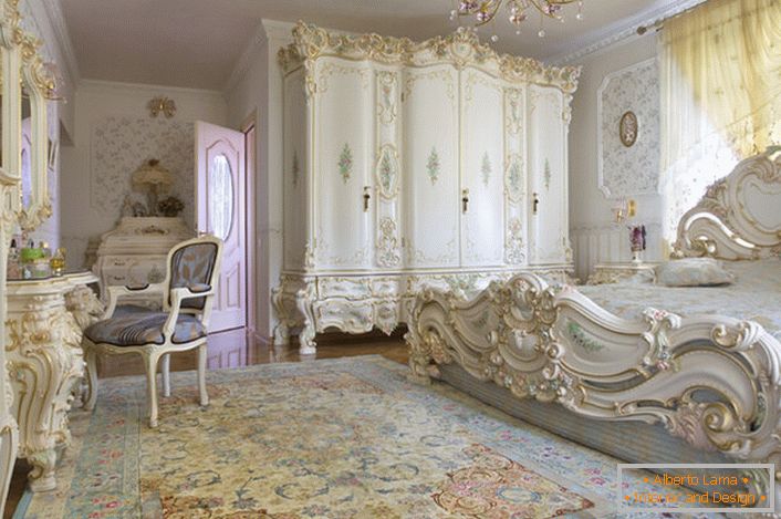 Schneeweißes Schlafzimmer mit geschnitzten massiven Möbeln aus Holz. Das Bett mit einem hohen Kopfteil am Kopfteil fügt sich elegant in den Innenraum im Barockstil ein.