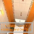 Die Kombination von weißen und orangefarbenen Fliesen im Design der Toilette