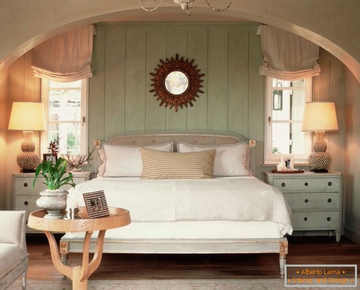 Familienschlafzimmer im Landhausstil. Die Wärme des Hauses, so gut wie möglich, wird durch ein weiches, volumetrisches Bett betont, das mit Kissen bedeckt ist.