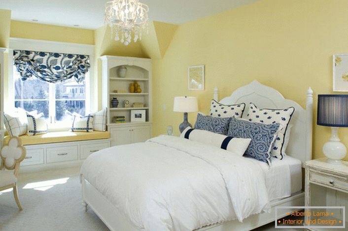 Die verblasste gelbe Farbe des Finish harmoniert mit den weißen und blauen Elementen des Dekors. Eine ungewöhnliche Kombination ist eine mutige Lösung für ein Schlafzimmer im Landhausstil.