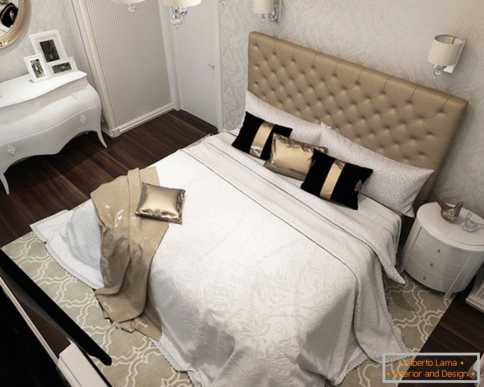 Im Zentrum der Designkomposition steht ein Bett mit einem hohen, gepolsterten, weichen Kopfteil. Die pompöse Art-Deco-Stil zeigt sich in der Verwendung von teuren Stoffen für die Dekoration, so auf dem Bett sehen wir Kissen mit Satin Kissenbezüge und schicke Bettwäsche.