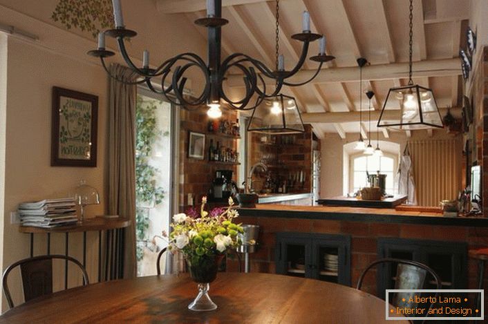 Der Ess- und Küchenbereich ist im Landhausstil eingerichtet. Bemerkenswert ist ein Kronleuchter über dem Tisch, der den Raum mit Hilfe von gewöhnlichen Wachskerzen beleuchtet. Dünne Designidee, denn im Raum gibt es auch eine traditionelle Beleuchtung, die vom Stromnetz aus arbeitet.