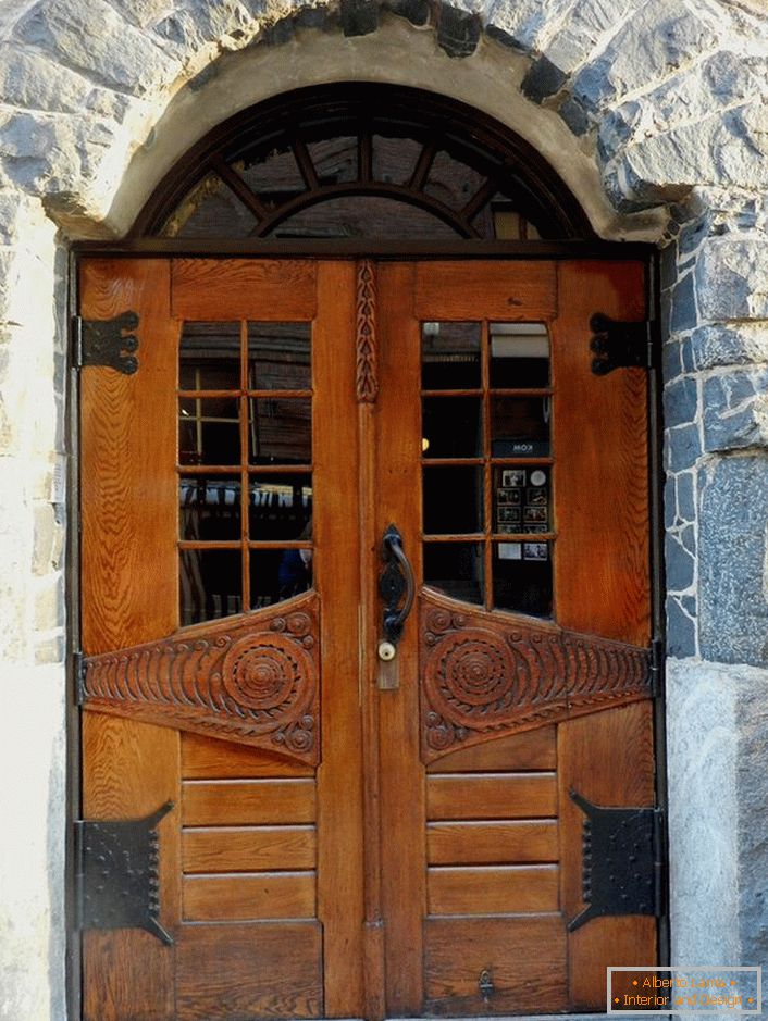 Türen im Jugendstil schmücken die Eingangstür eines Landhauses mit einer Fassade aus Naturstein. 