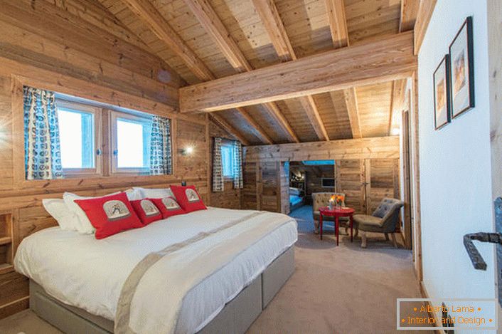 Ein geräumiges Schlafzimmer im zweiten Stock eines Landhauses aus einem Holzblockhaus. В соответствии со стилем кантри искусственный свет в комнате приглушен. 